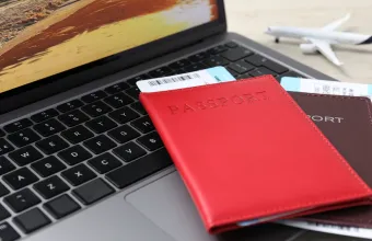 Passports, flight tickets, plane model and laptop on table