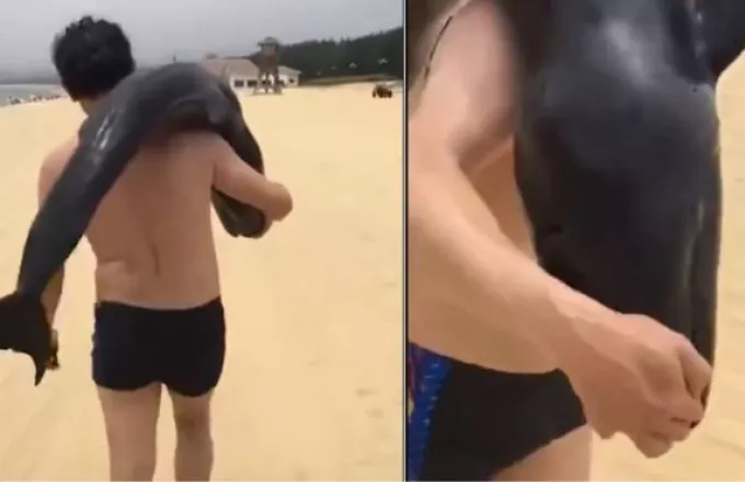 Πήρε στον ώμο του ετοιμοθάνατο δελφίνι και έφυγε από την παραλία (βίντεο)
