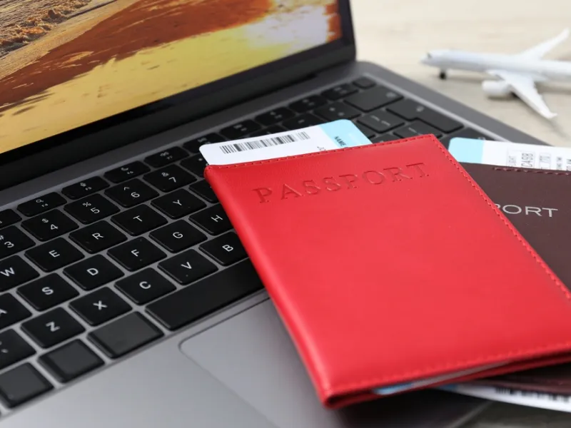 Passports, flight tickets, plane model and laptop on table