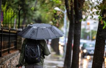 Άντρας με ομπρέλα περπατάει στη βροχή 