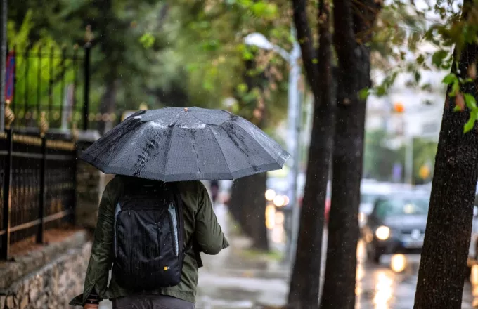 Άντρας με ομπρέλα περπατάει στη βροχή 
