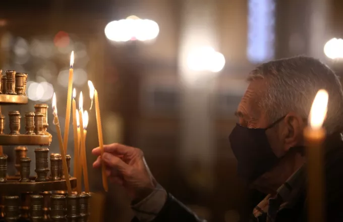 Πιστός ανάβει κερί σε εκκλησία 